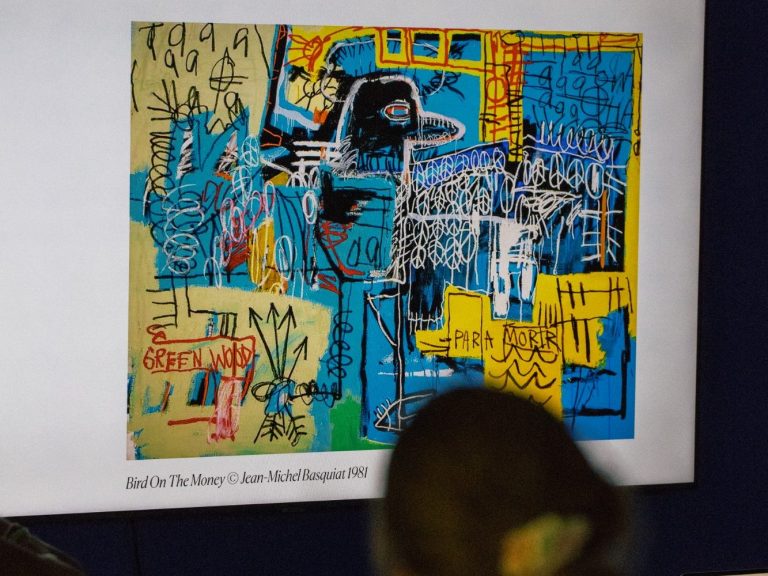 A child is looking at a colourful image from a projector. The image is Bird On The Money by Jean-Michel Basquiat, 19881