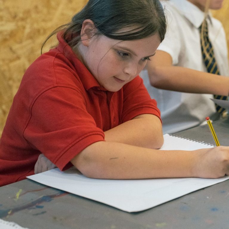 An image of a child drawing in a workshop environment